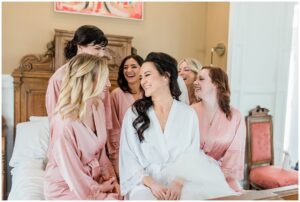 bride sitting with her bridesmaids in blush pink robes