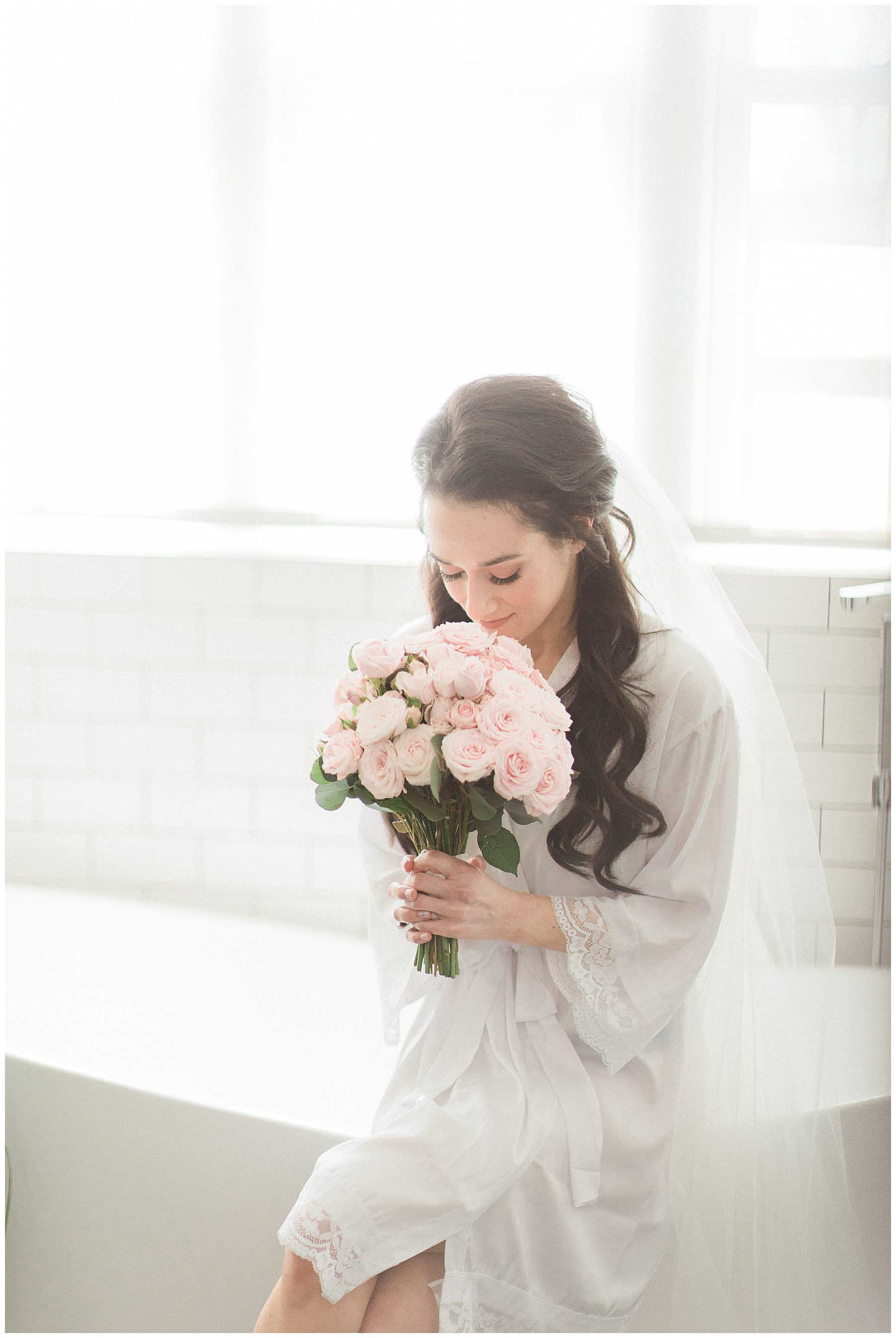 bride smelling the blush pink roses from her wedding bouquet