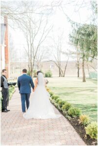 couple hold hands as they walk along brick path at Ryland Inn