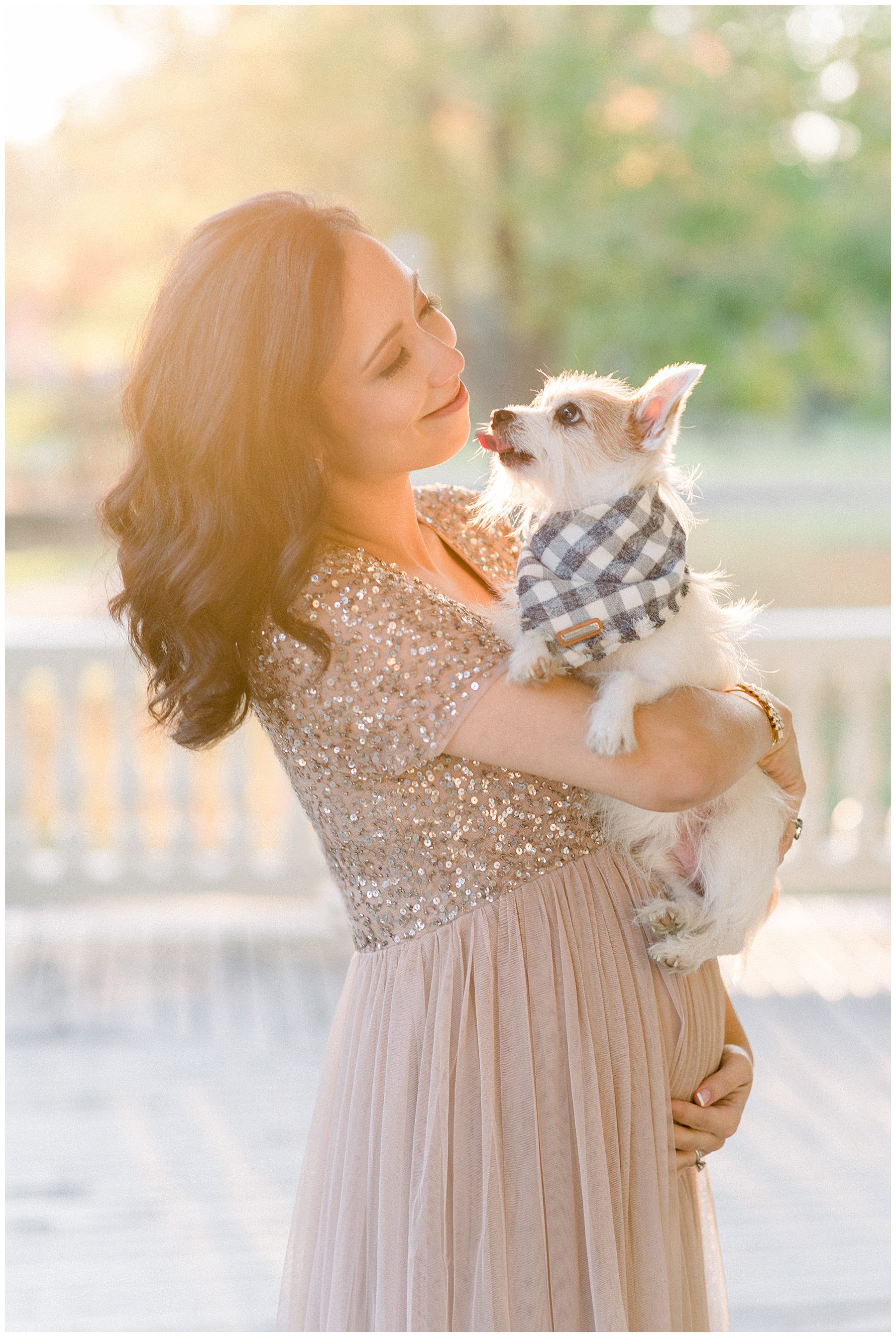 woman holds her dog during maternity session
