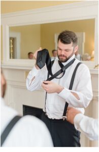 groom puts tie on before Late Summer Wedding at Cairnwood Estate
