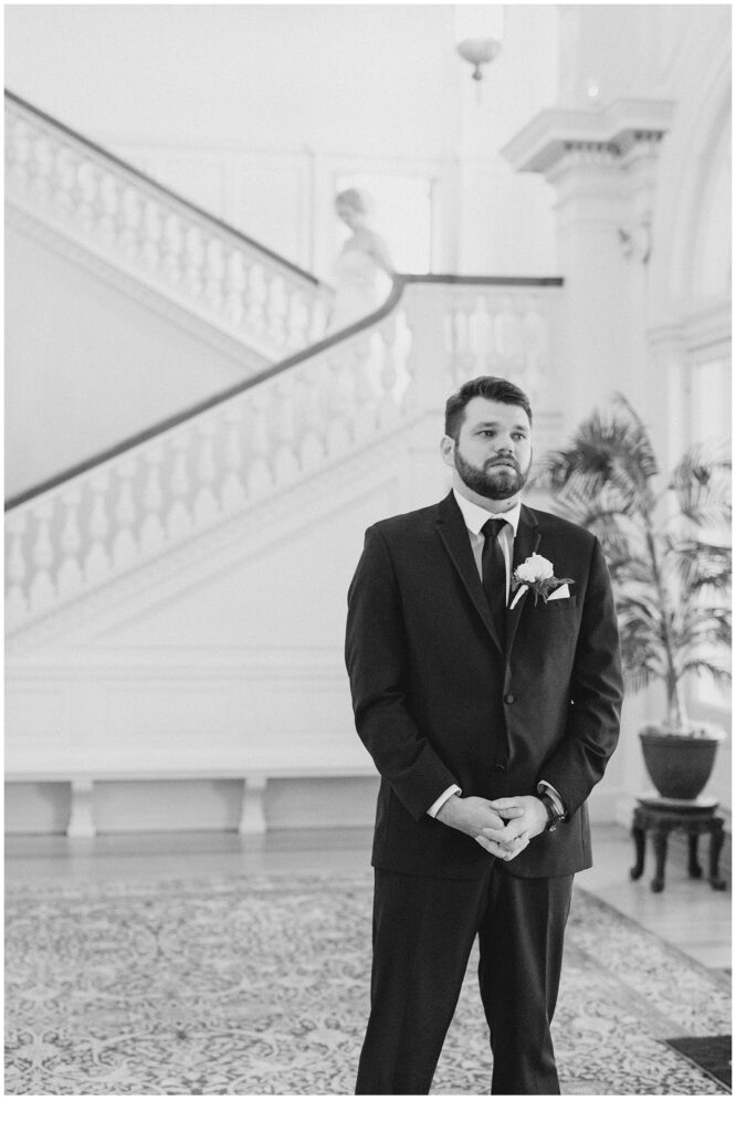 groom waiting for bride at bottom of stairs