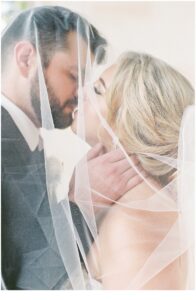 couple kiss under bride's veil