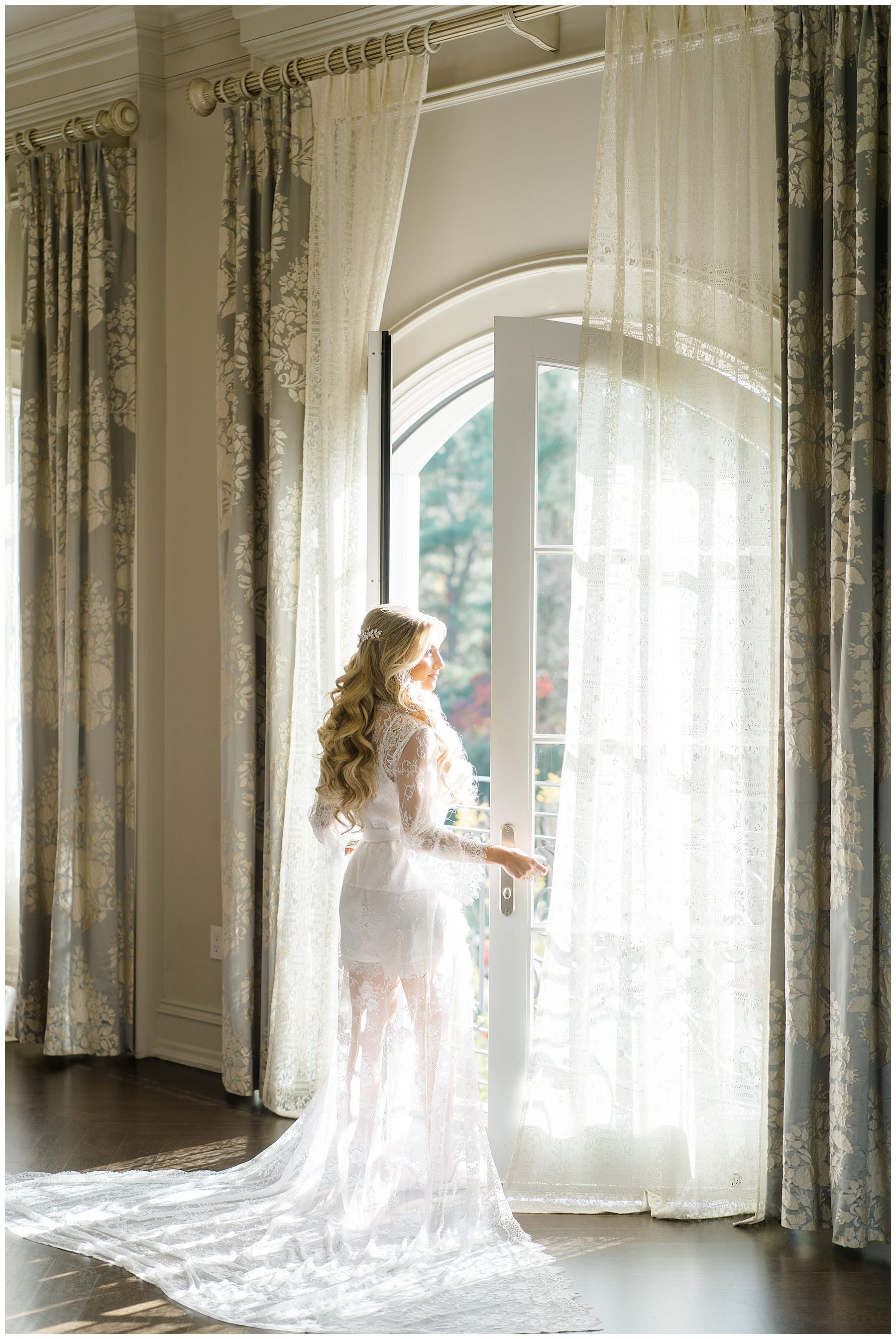 Bride looking out door in robe in bridal suite