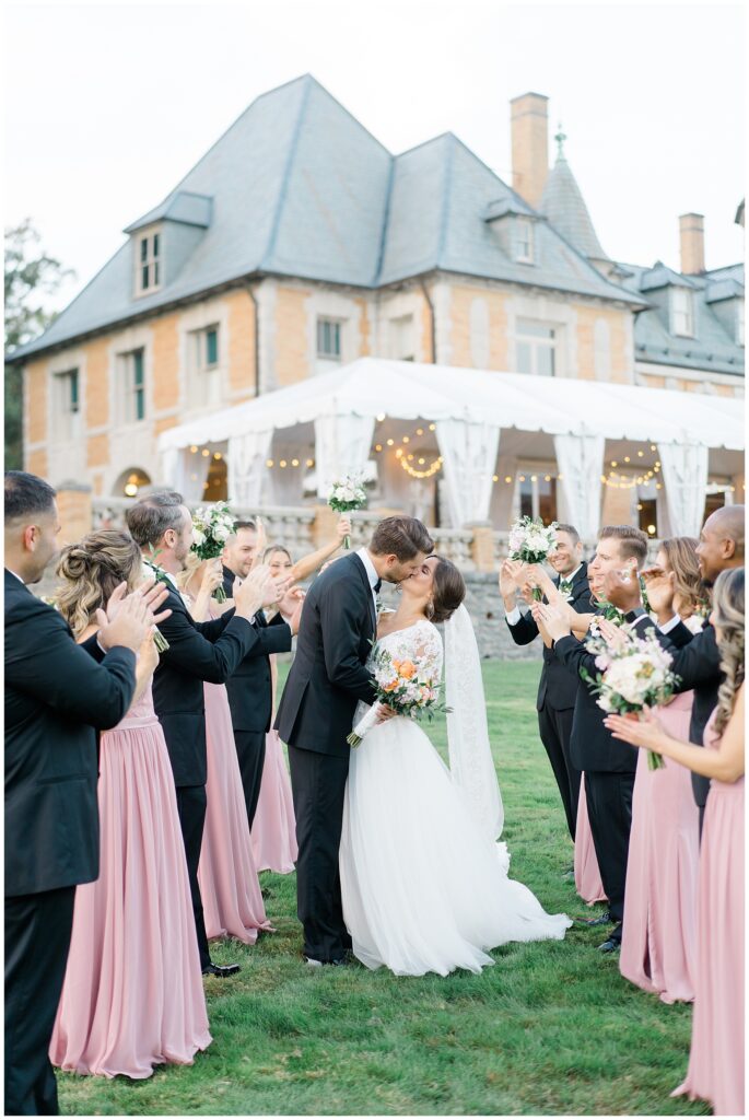 newlyweds kiss as bridal party claps around them