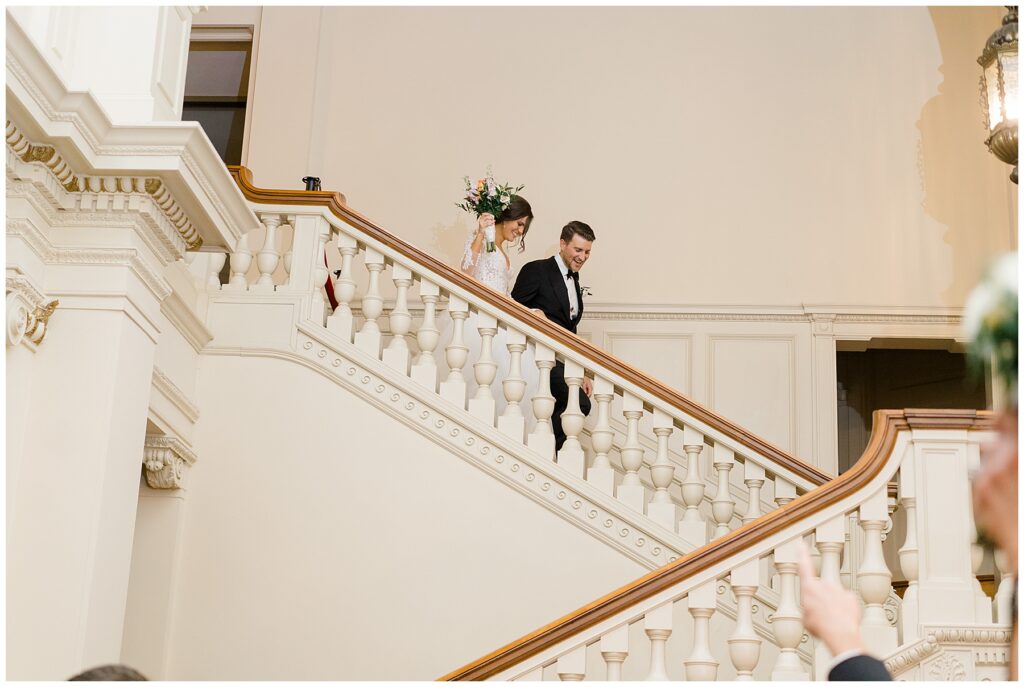 bride and groom walking down grand staircase of the Elegant Cairnwood Estate