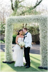 newlyweds under flower wedding arch