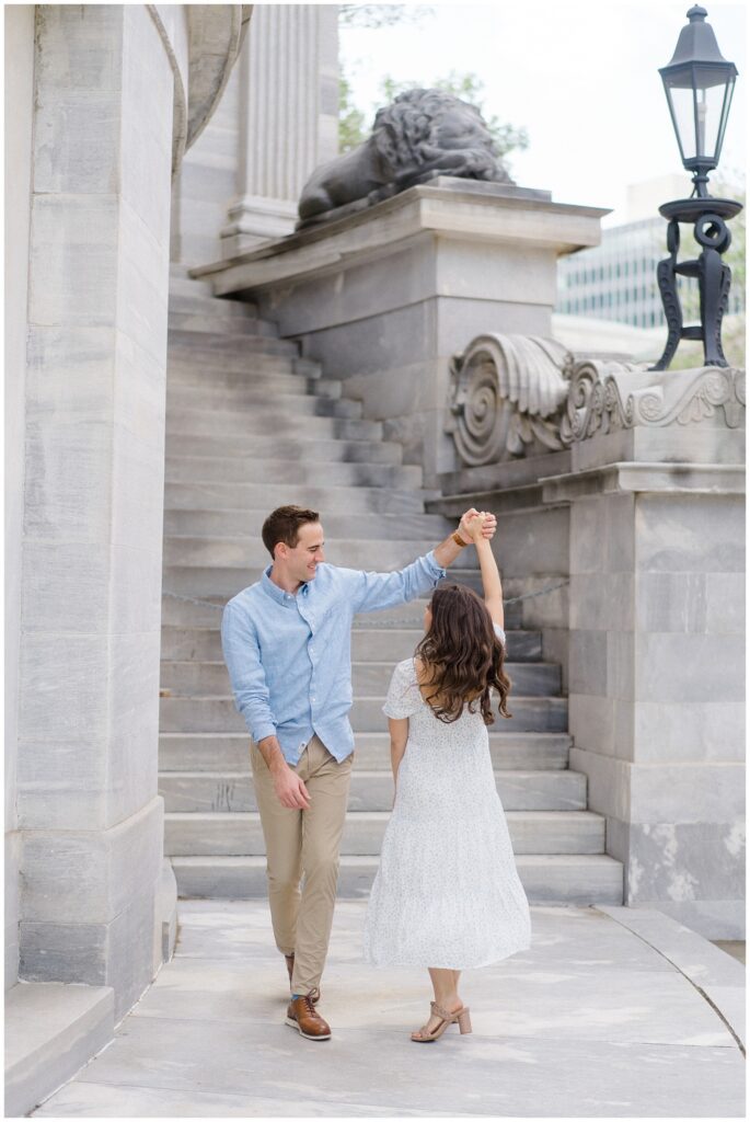 Man twirling woman along a beautiful building with a staircase behind