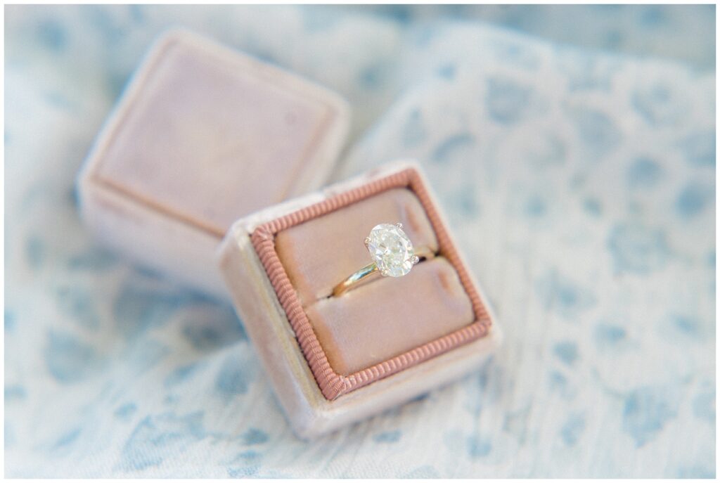 Oval engagement ring with gold band in pink ring box