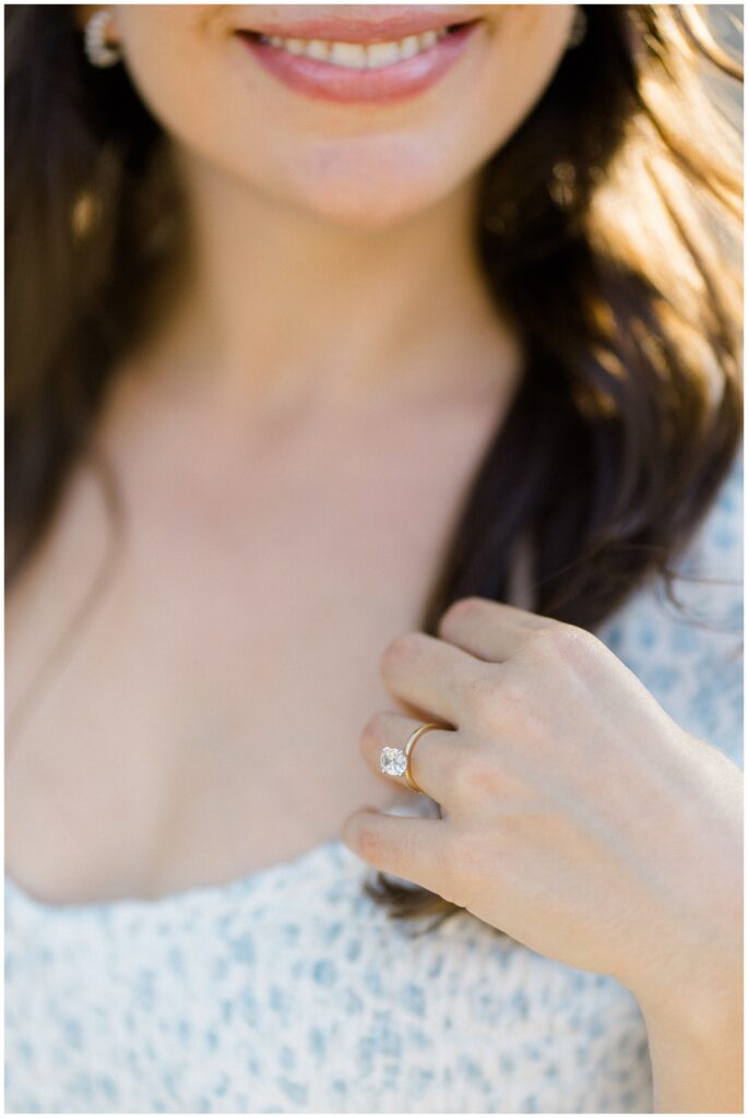 Oval engagement ring with gold band on woman's hand touching hair