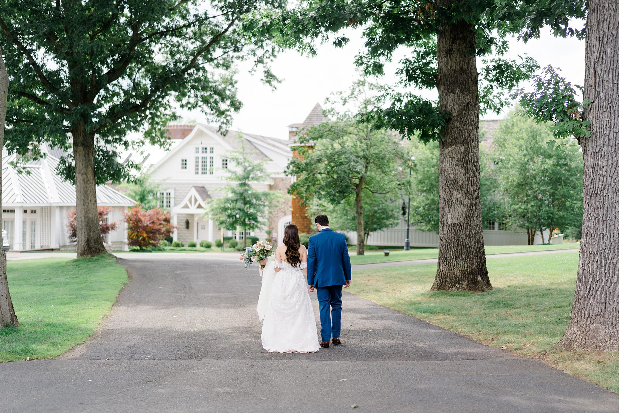 newlyweds hold hands as the walk the property of Ryland Inn