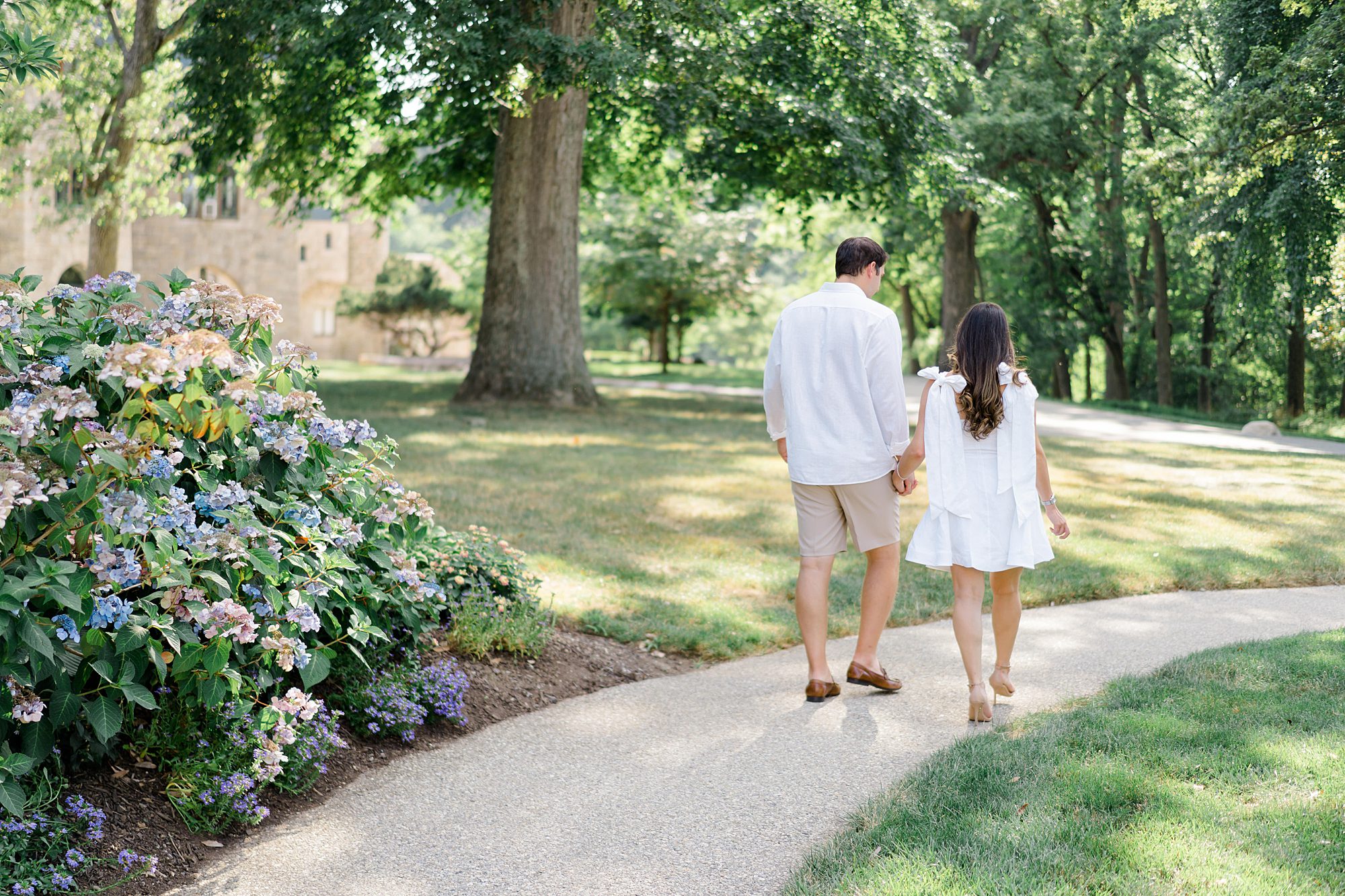 engaged couple walking along path holding hands at the Cairnwood Estate