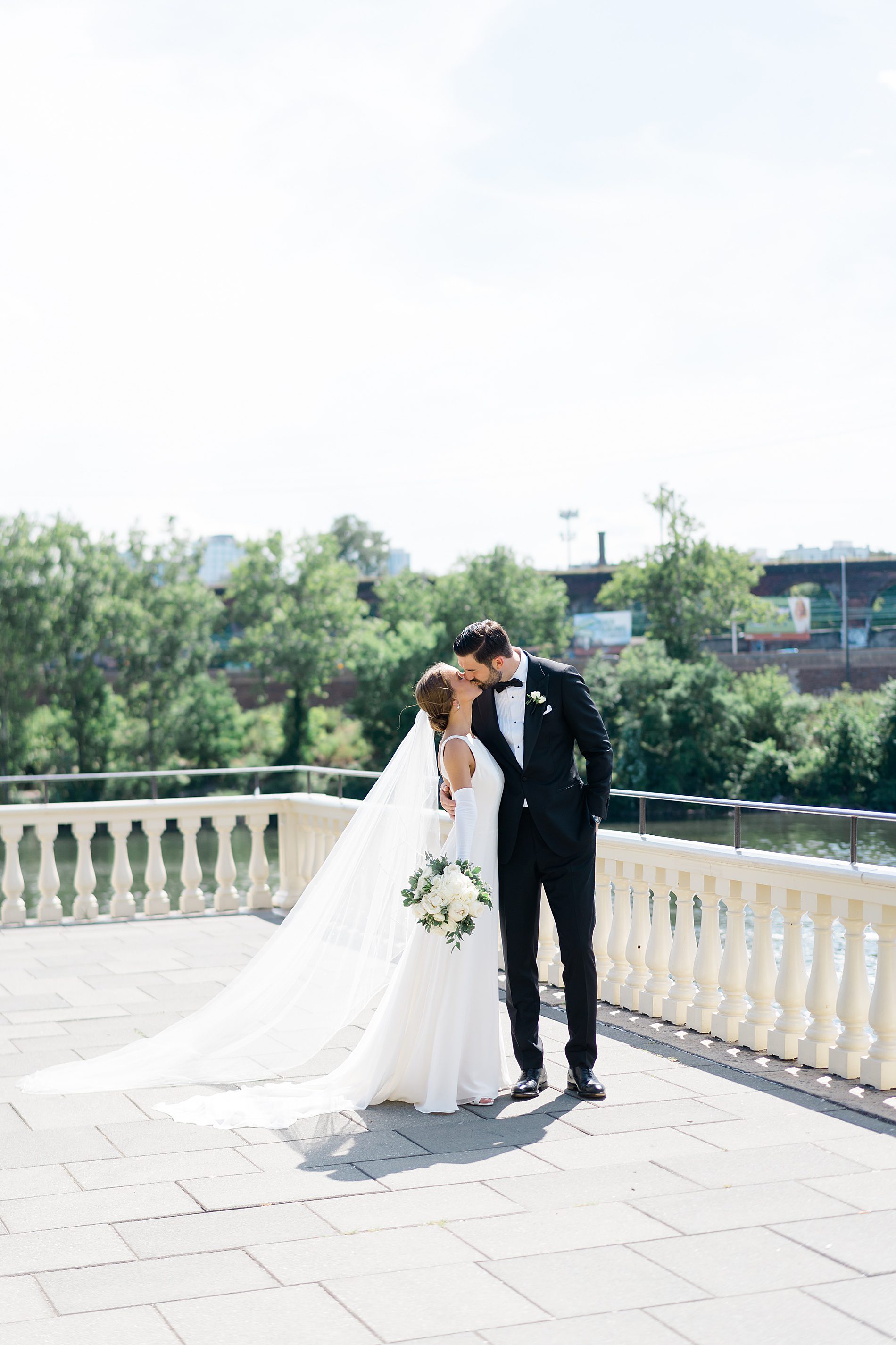 bride and groom kiss during wedding portraits on balcony