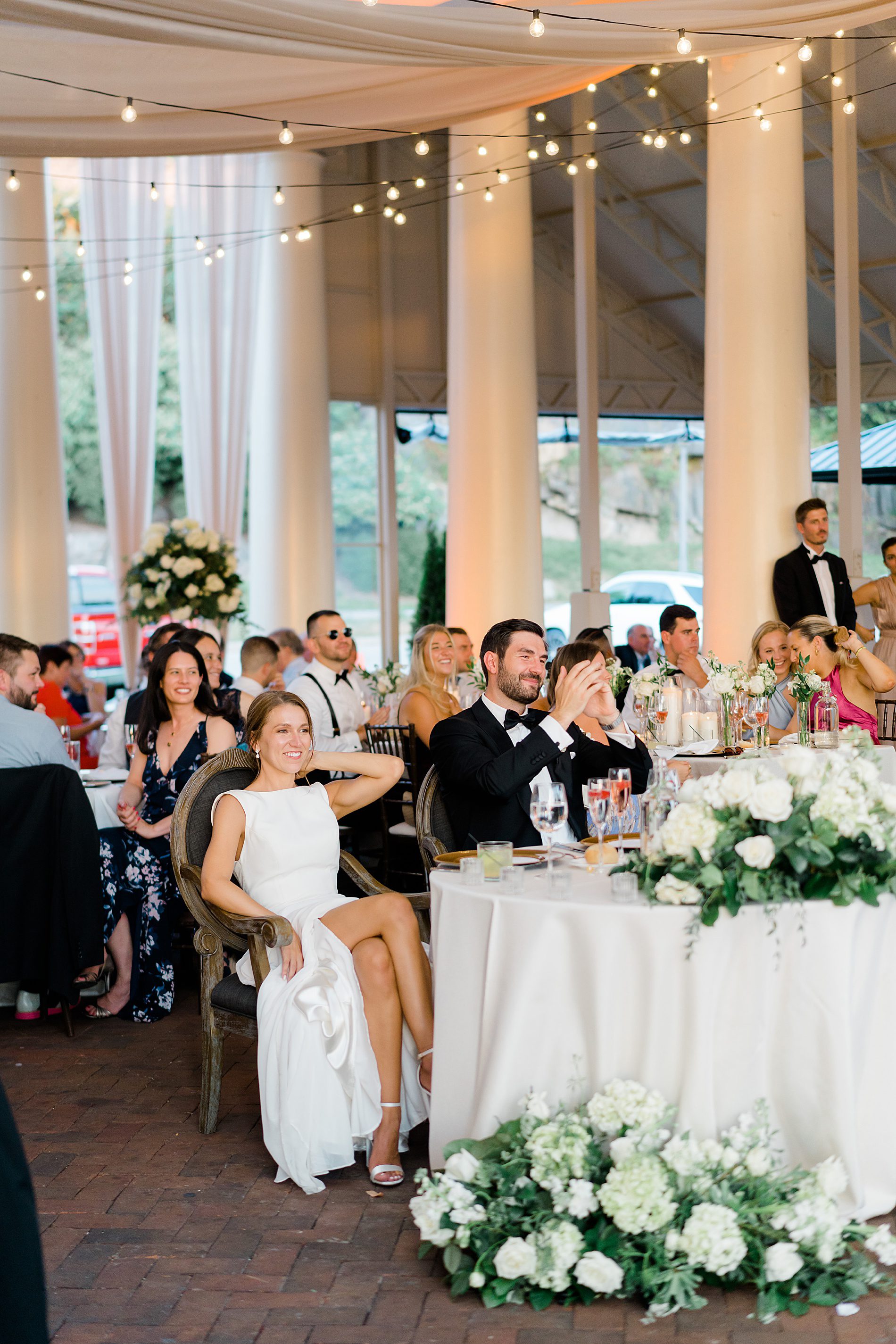 newlyweds listen to wedding toasts at reception