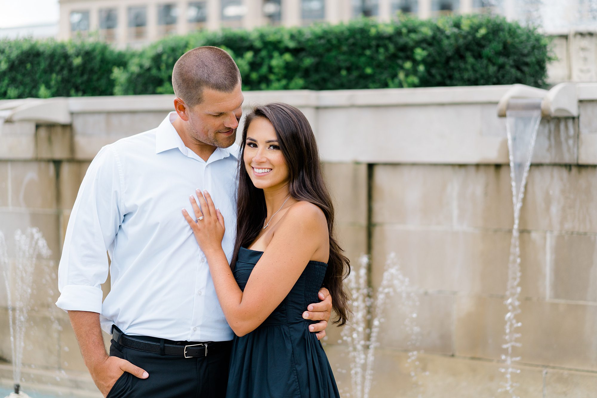 couple hug and stand near water fountain during PA engagement