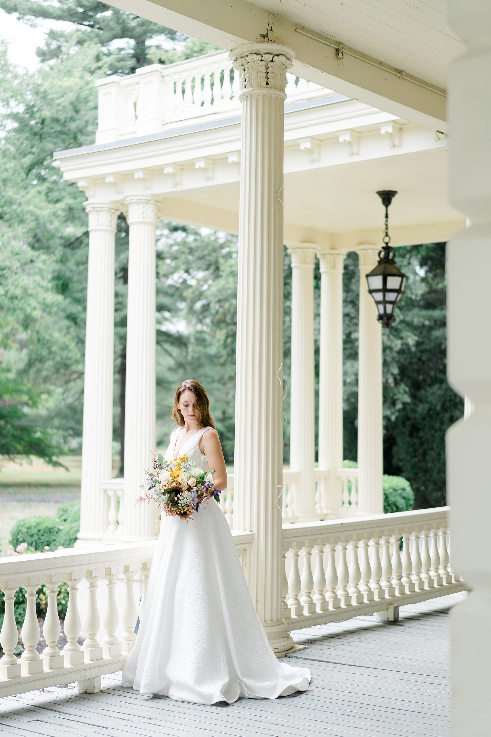 bride on the wrap around porch of mansion at Glen Foerd in Philadelphia
