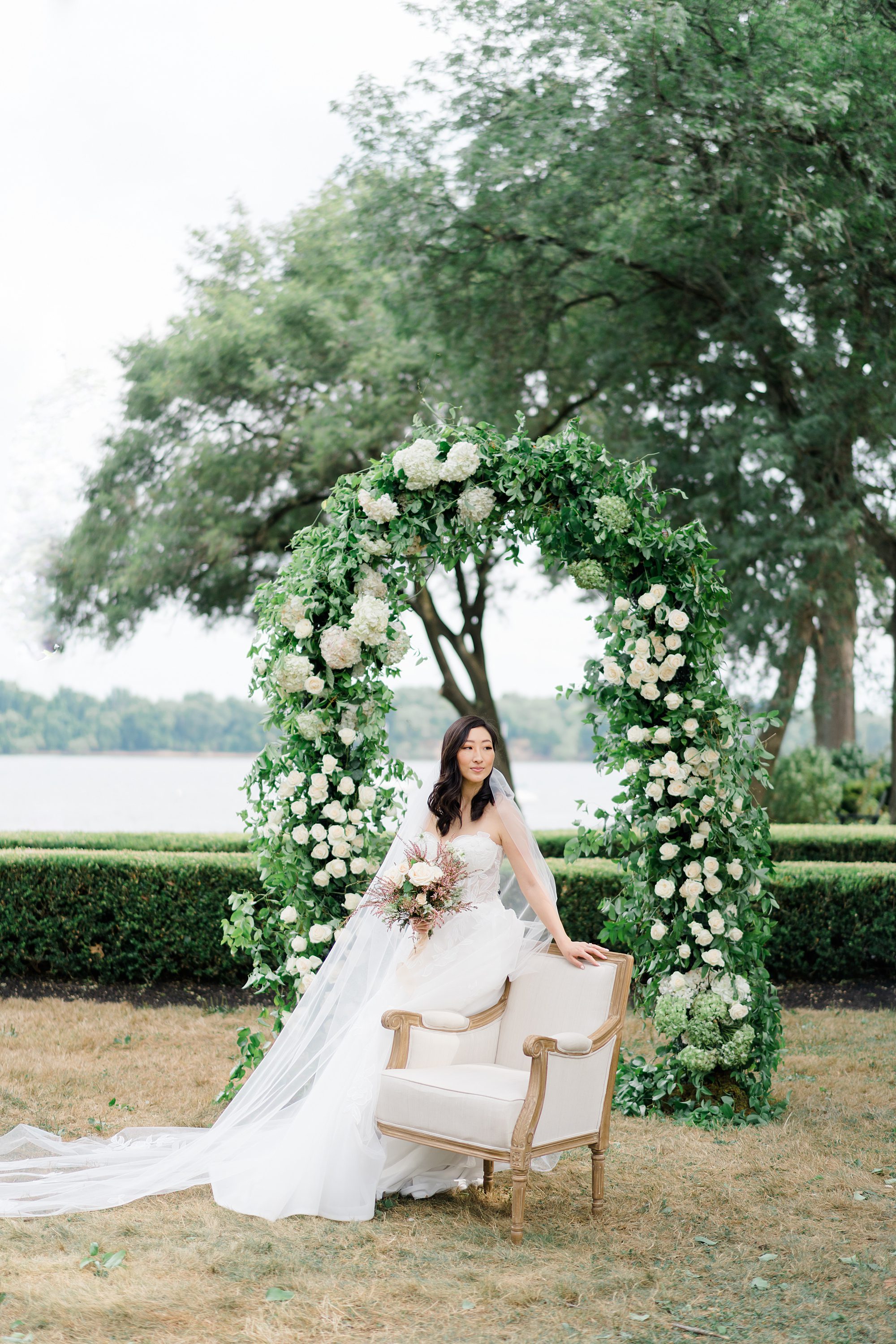 bride by floral wedding arch by Belovely