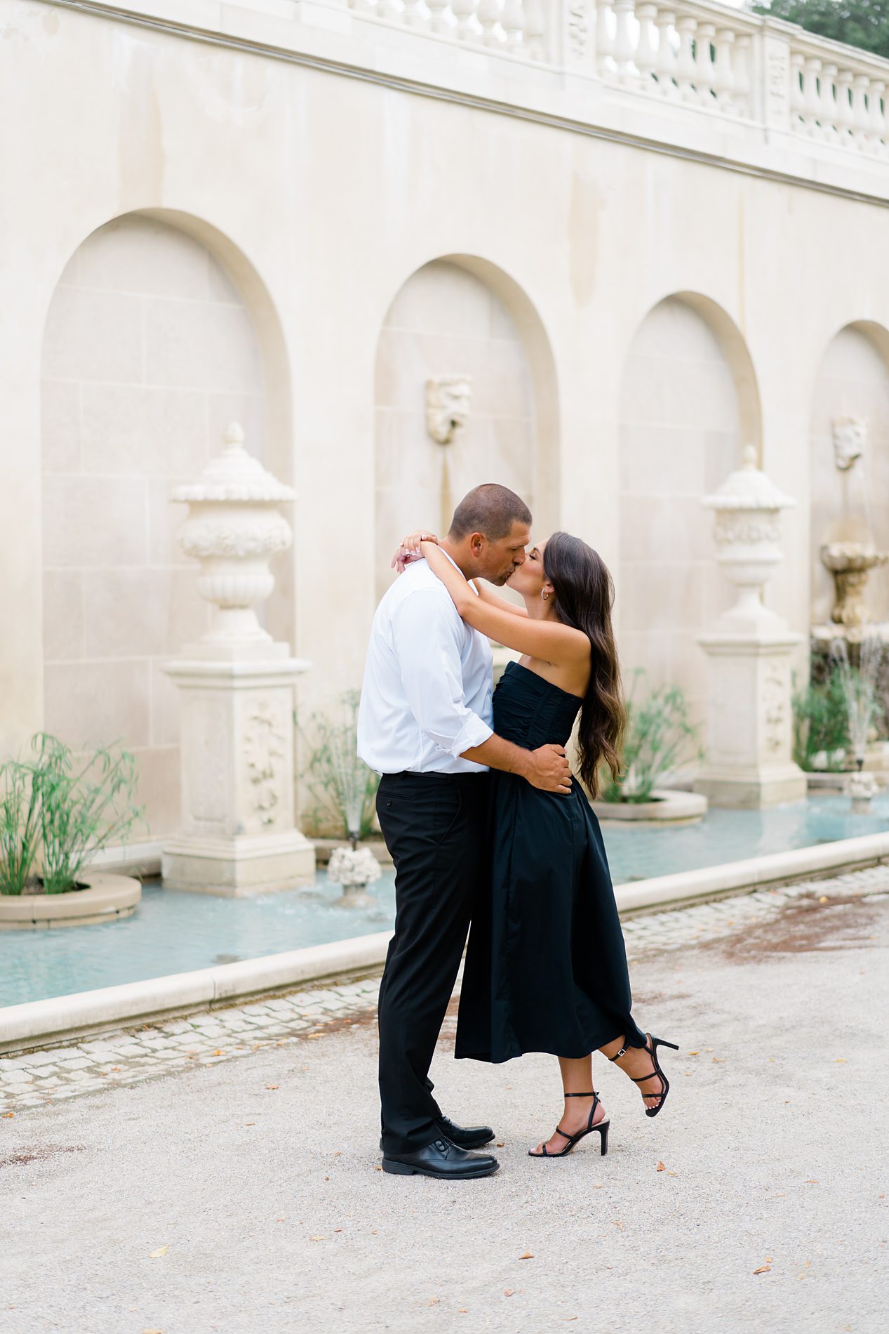 Couple kiss in front of water fountains at Longwood Gardens Engagement