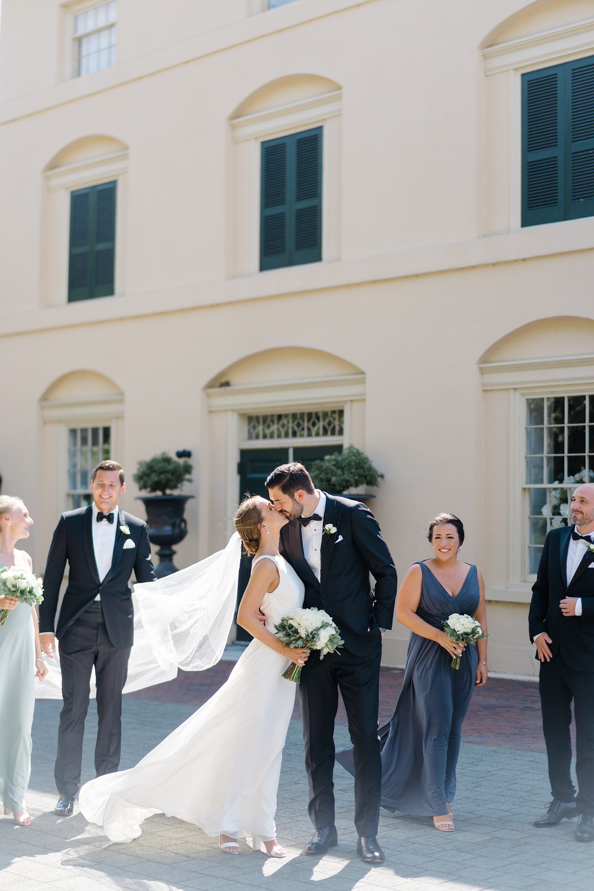 couple kiss with bridal party around them outside of Classic + Elegant Philadelphia Wedding venue Water Works