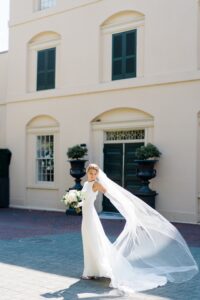 bride stands outside Water Works in dress with veil flowing behind her