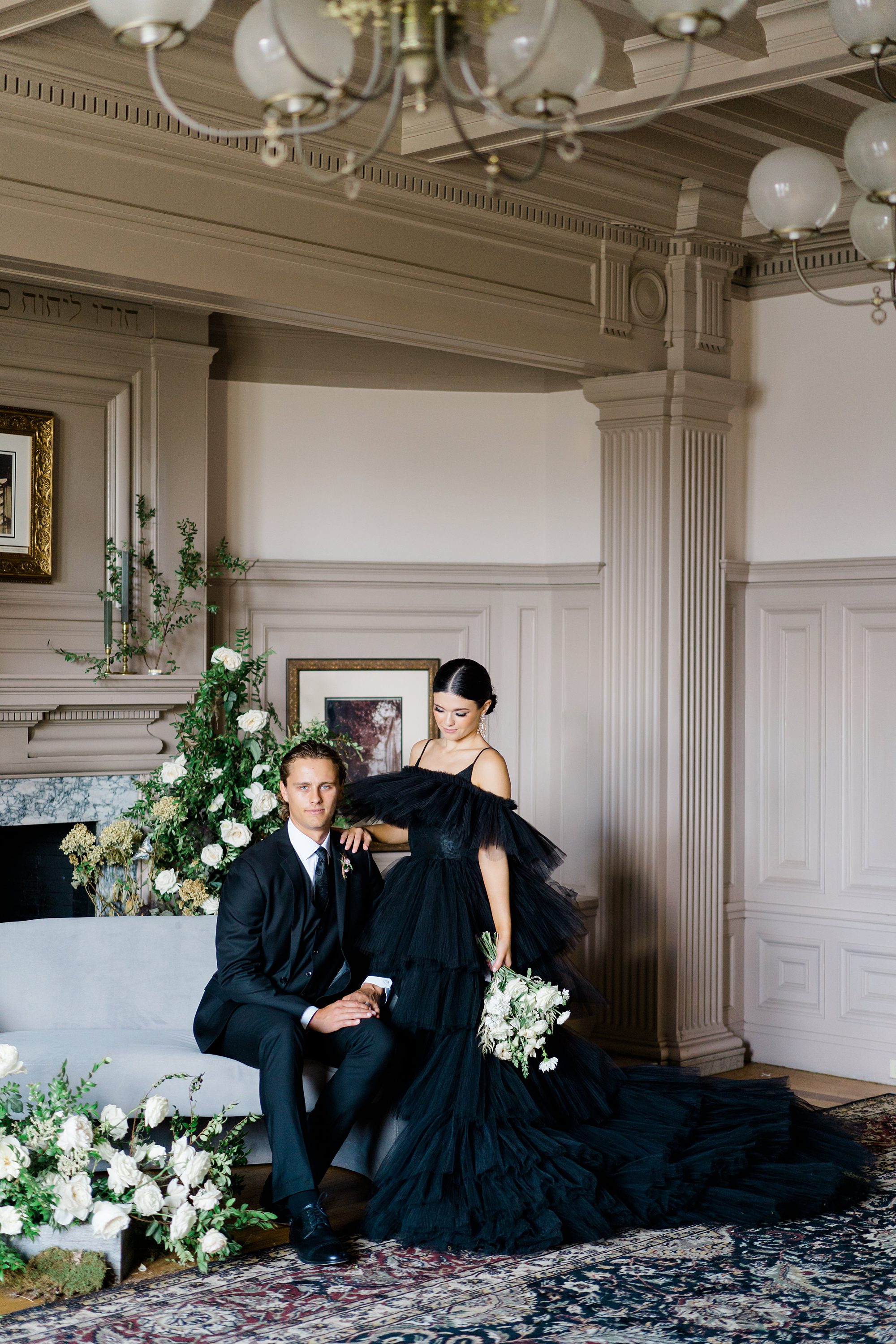 bride in high fashion black wedding dress sits with groom