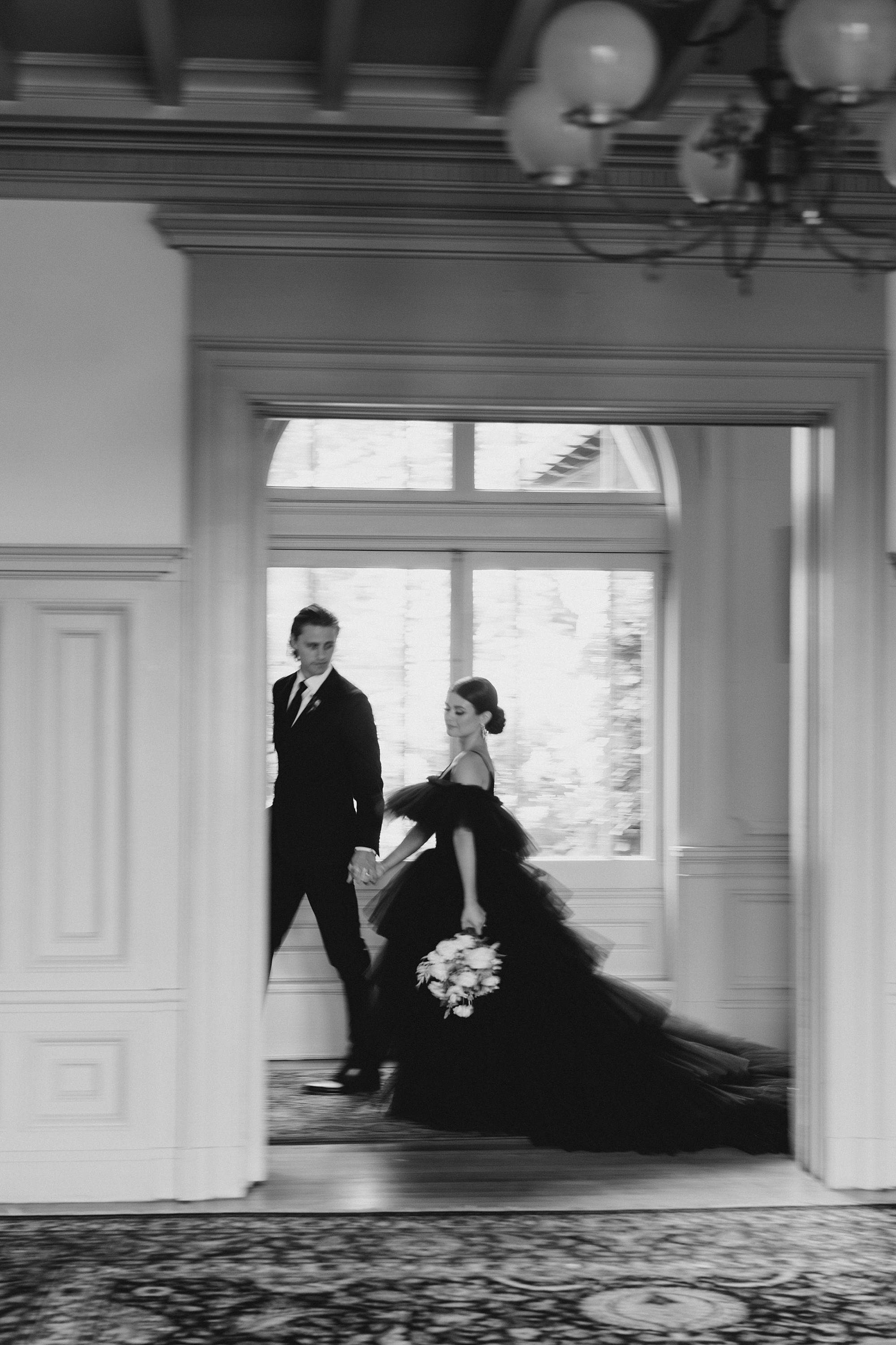 groom leads his bride in black wedding dress