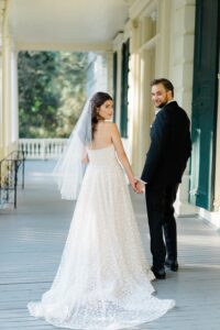 newlyweds hold hands walking on porch