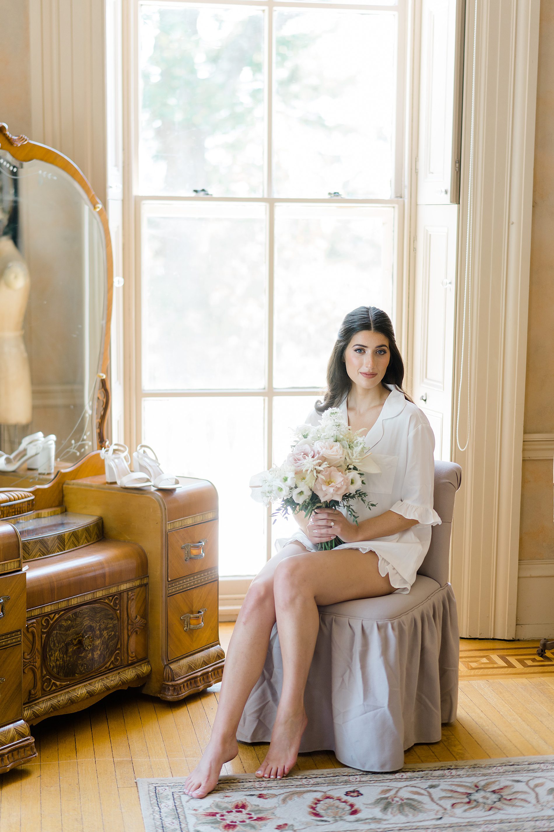 bride sitting on stool holding wedding bouquet