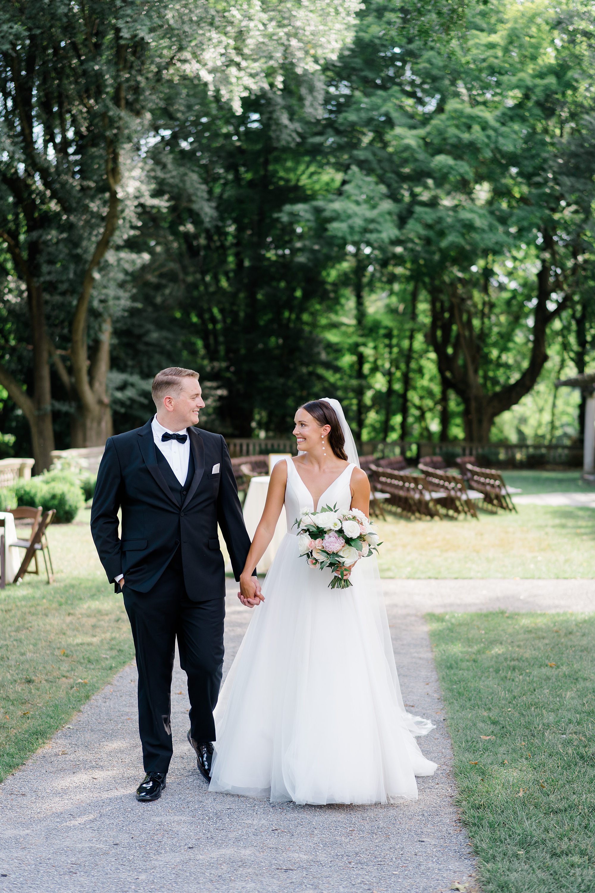 bride and groom hold hands as they walk through Garden at Curtis Arboretum