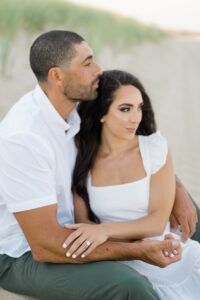 couple sit on the sand during engagement portraits