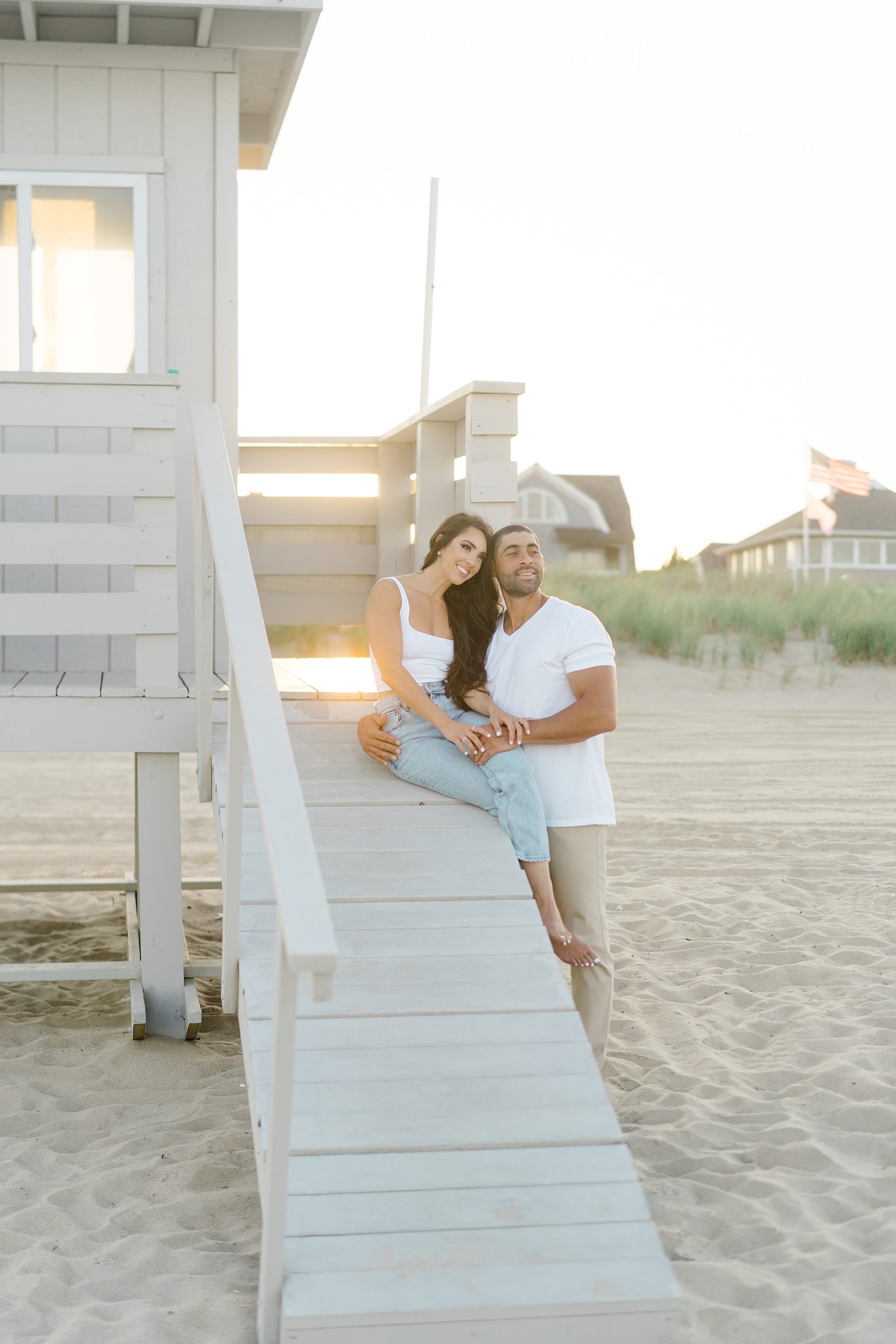 engaged couple sit on the wooden ramp of beach house