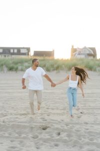 couple hold hands and run down the Jersey Shore beach