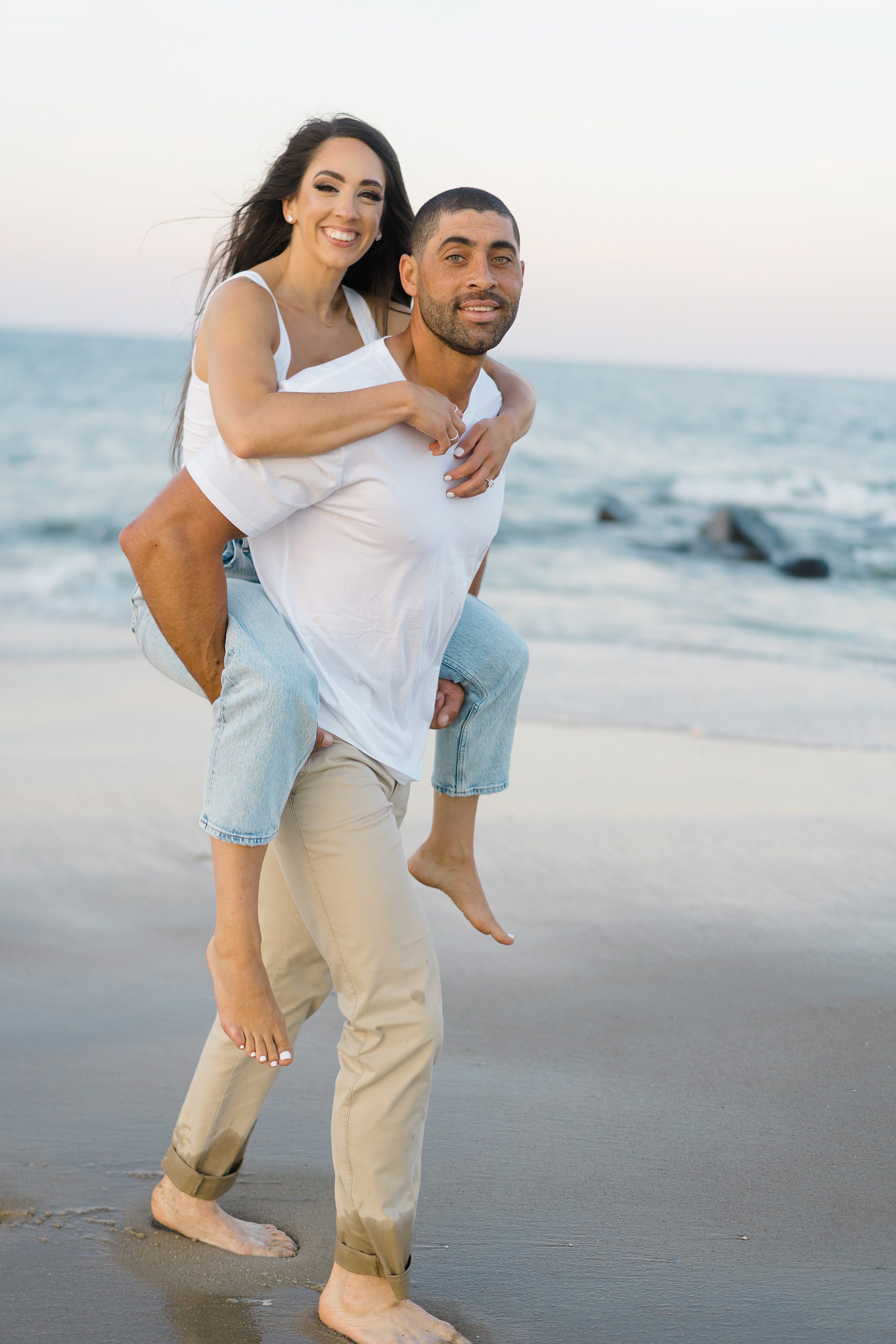 man carries his fiance on his back during Jersey Shore Beach Engagement