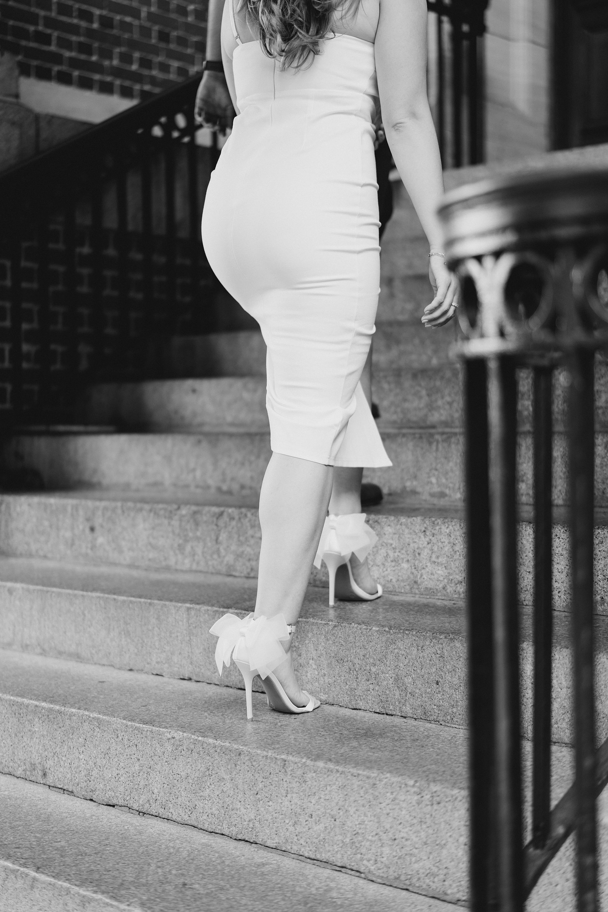 woman walks up stairs in white heels