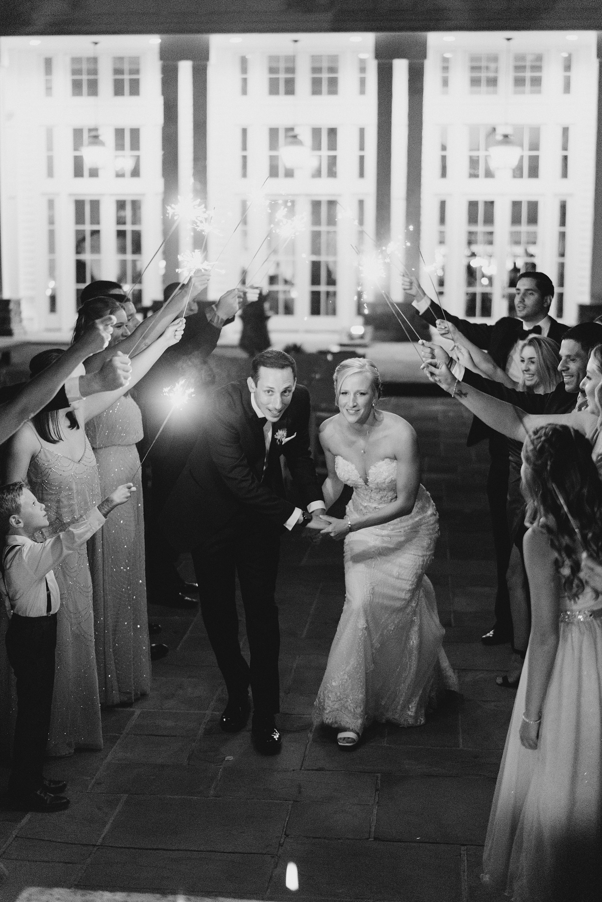 guests hold up sparklers as couple exit the reception