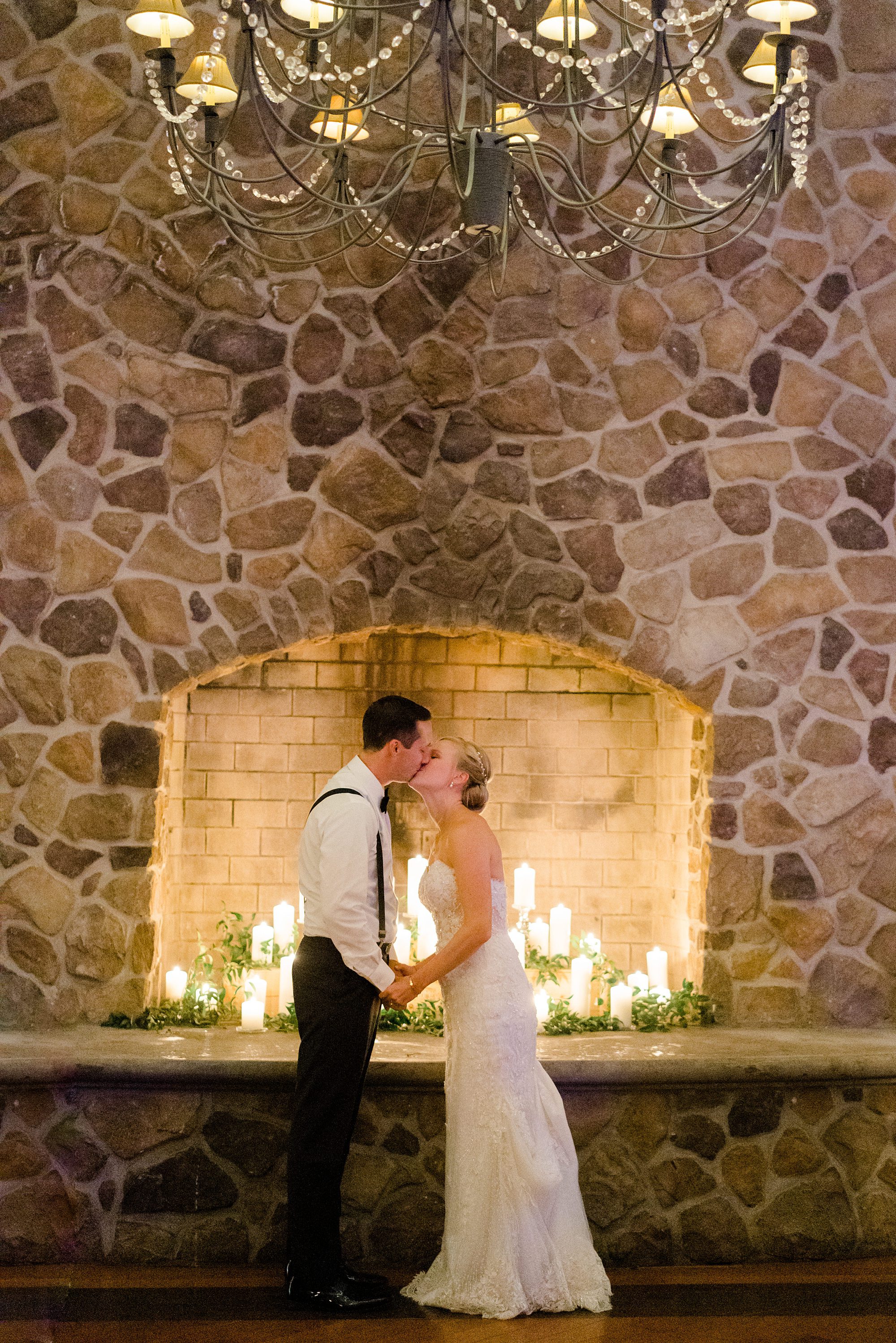 bride and groom kiss in front of stone fireplace at The Ryland Inn