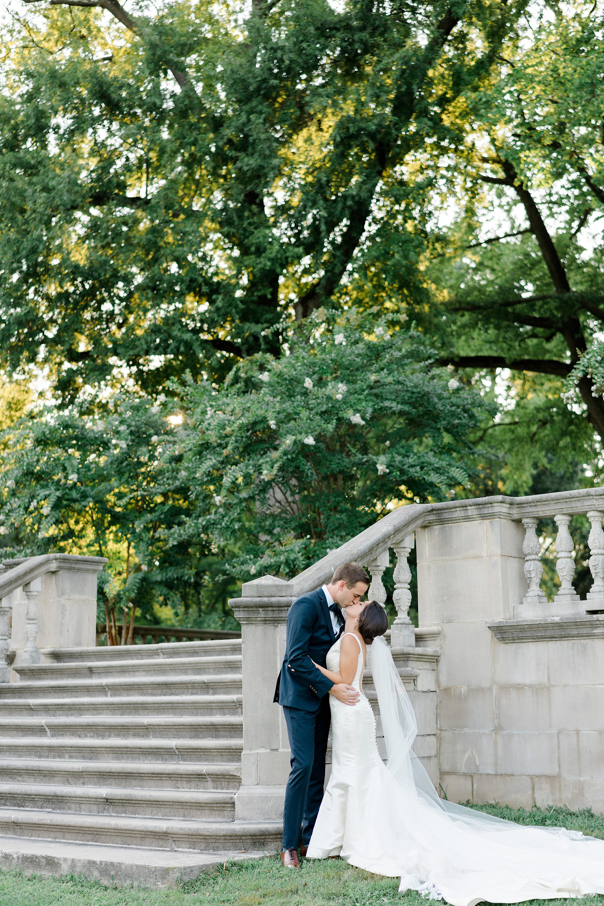 couple kiss at the bottom of stairs after wedding ceremony