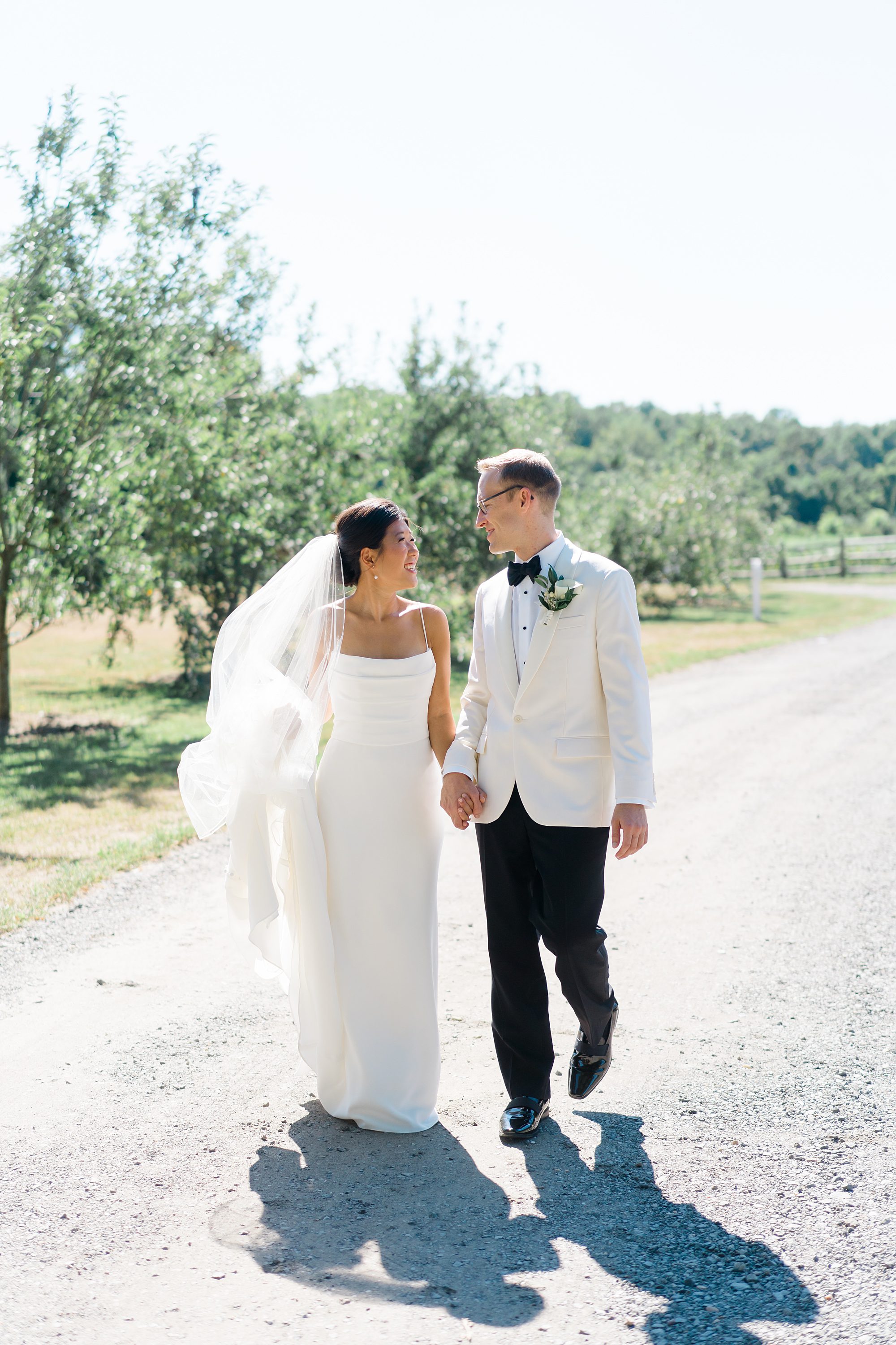 bride and groom hold hands walking down road