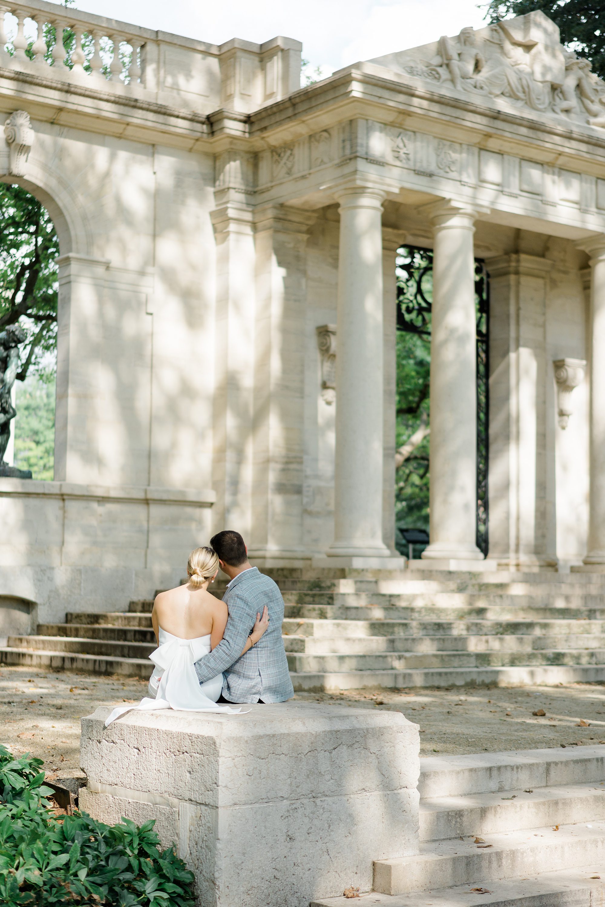 couple sit on stairs during Engagement session at Rodin Museum