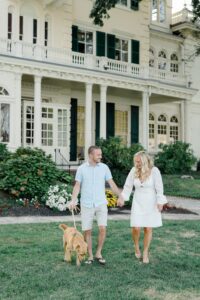 engaged couple walk their dog while holding hands