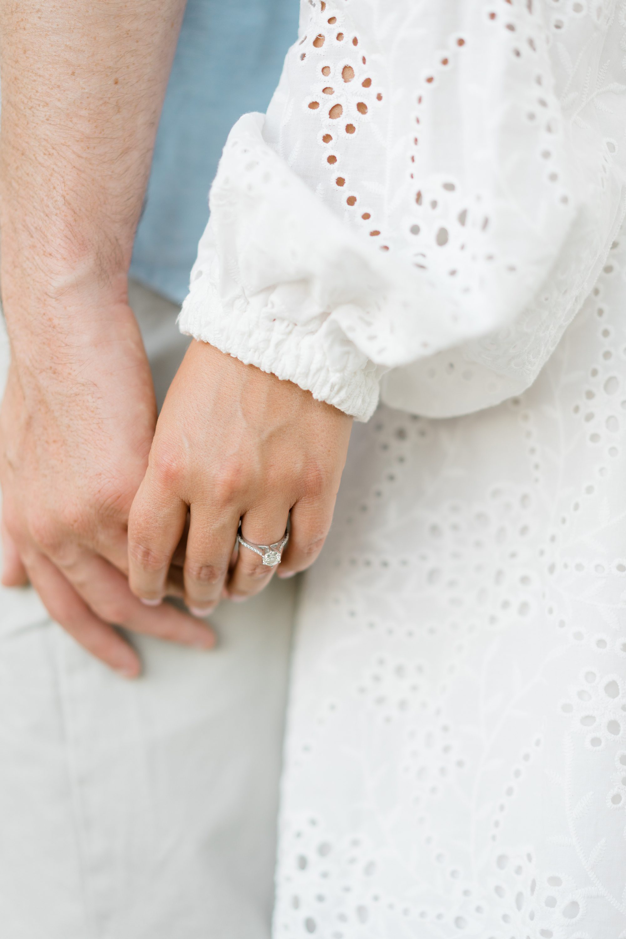 couple holding hands with engagement ring on