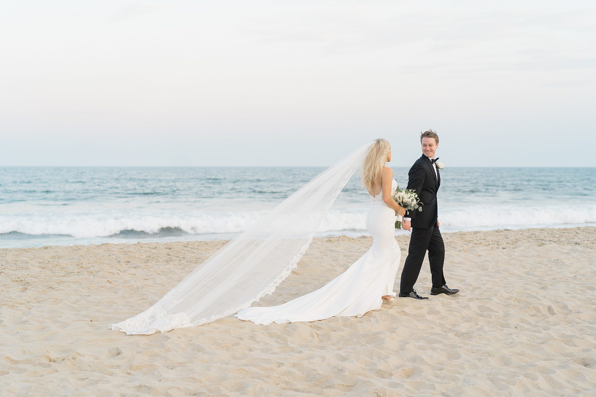 newlyweds walk on the beach holding hands
