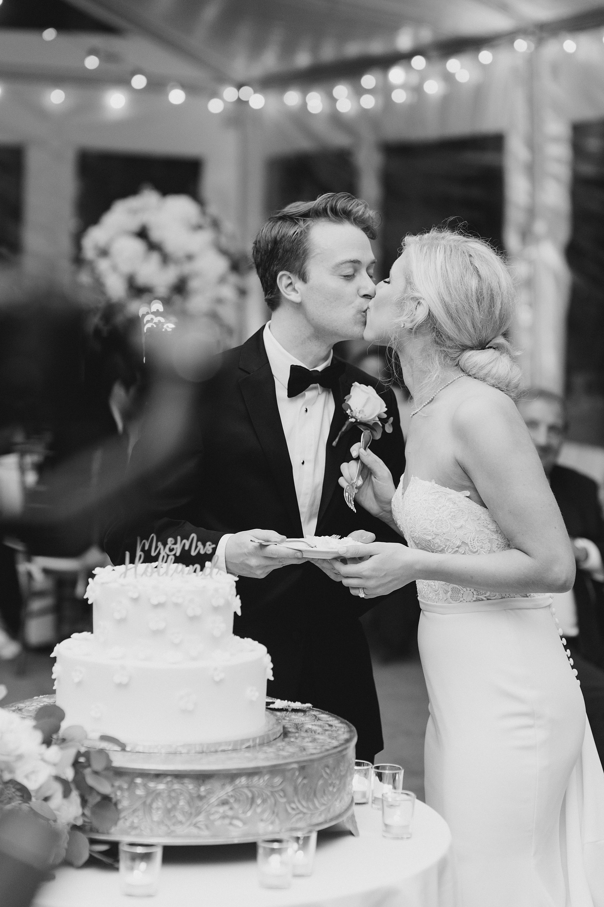 newlyweds kiss while cutting wedding cake