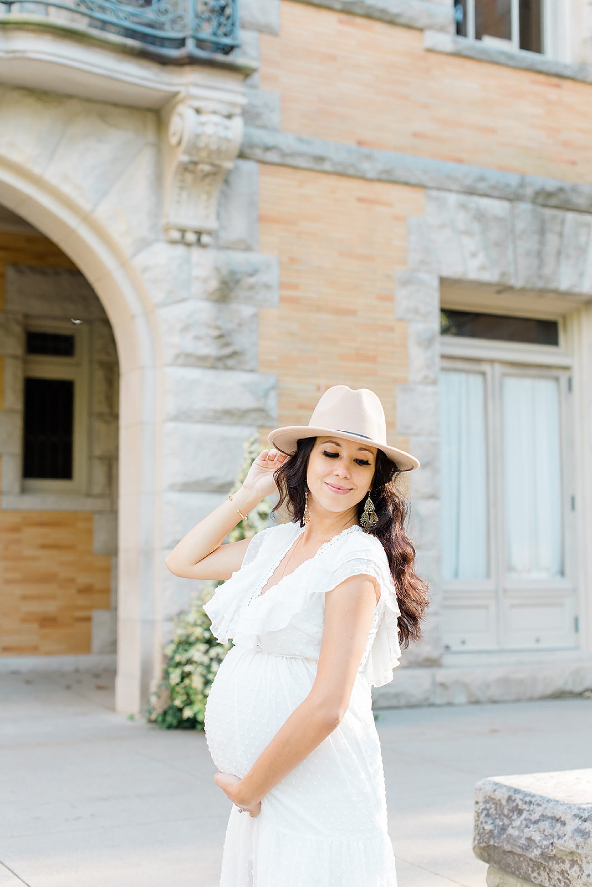 woman in white, flowy maternity dress and hat