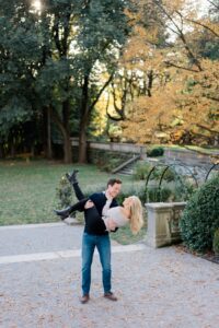 candid engagement portraits of man lifting his fiance up at Curtis Arboretum