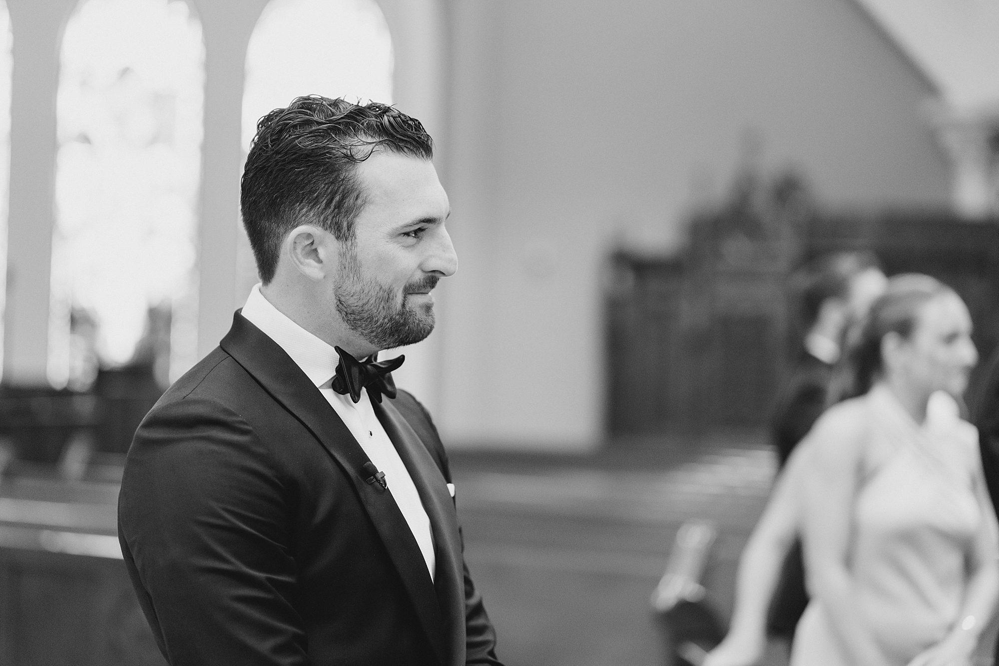 groom watches his bride walk down the aisle