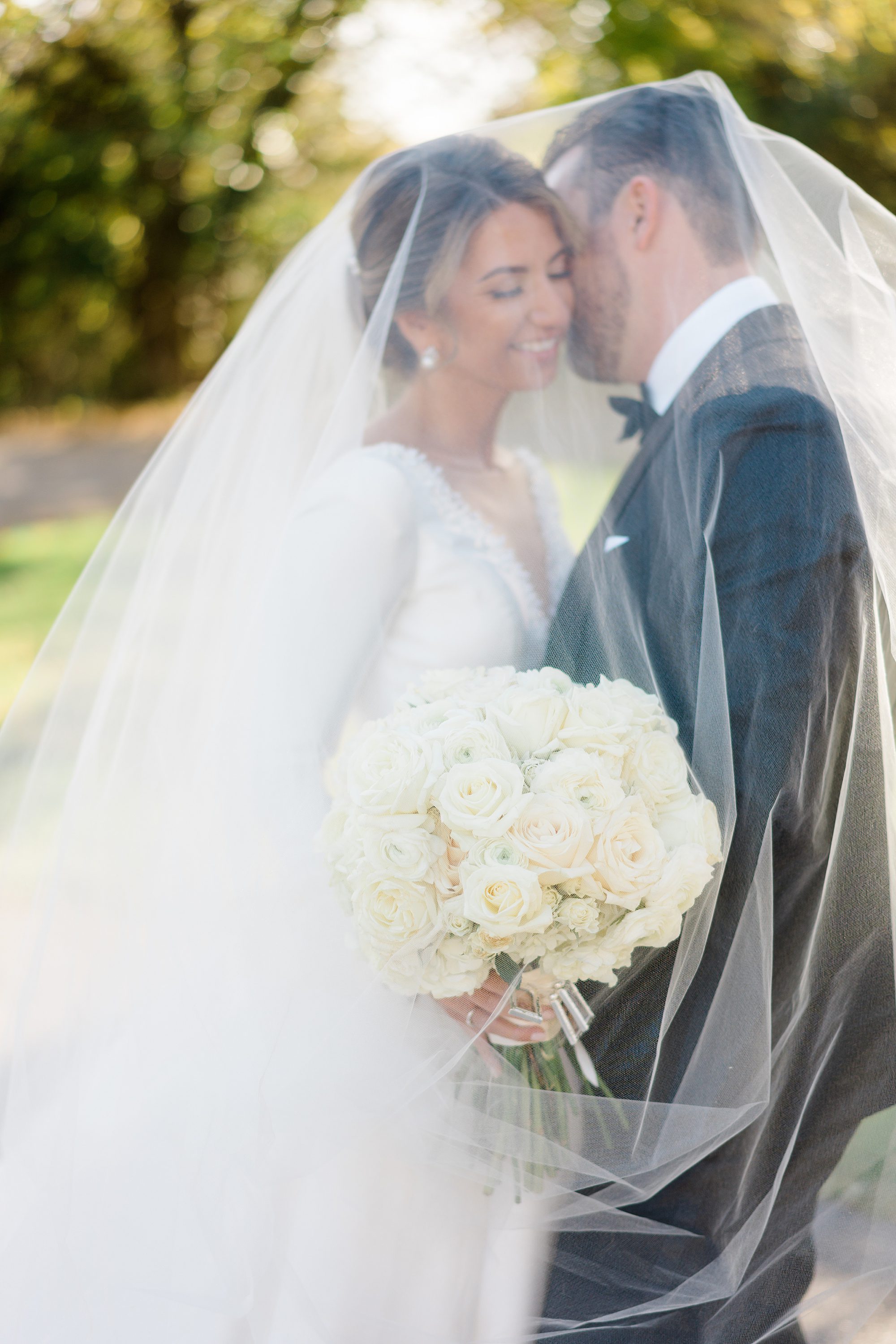 couple under bride's veil for wedding portraits