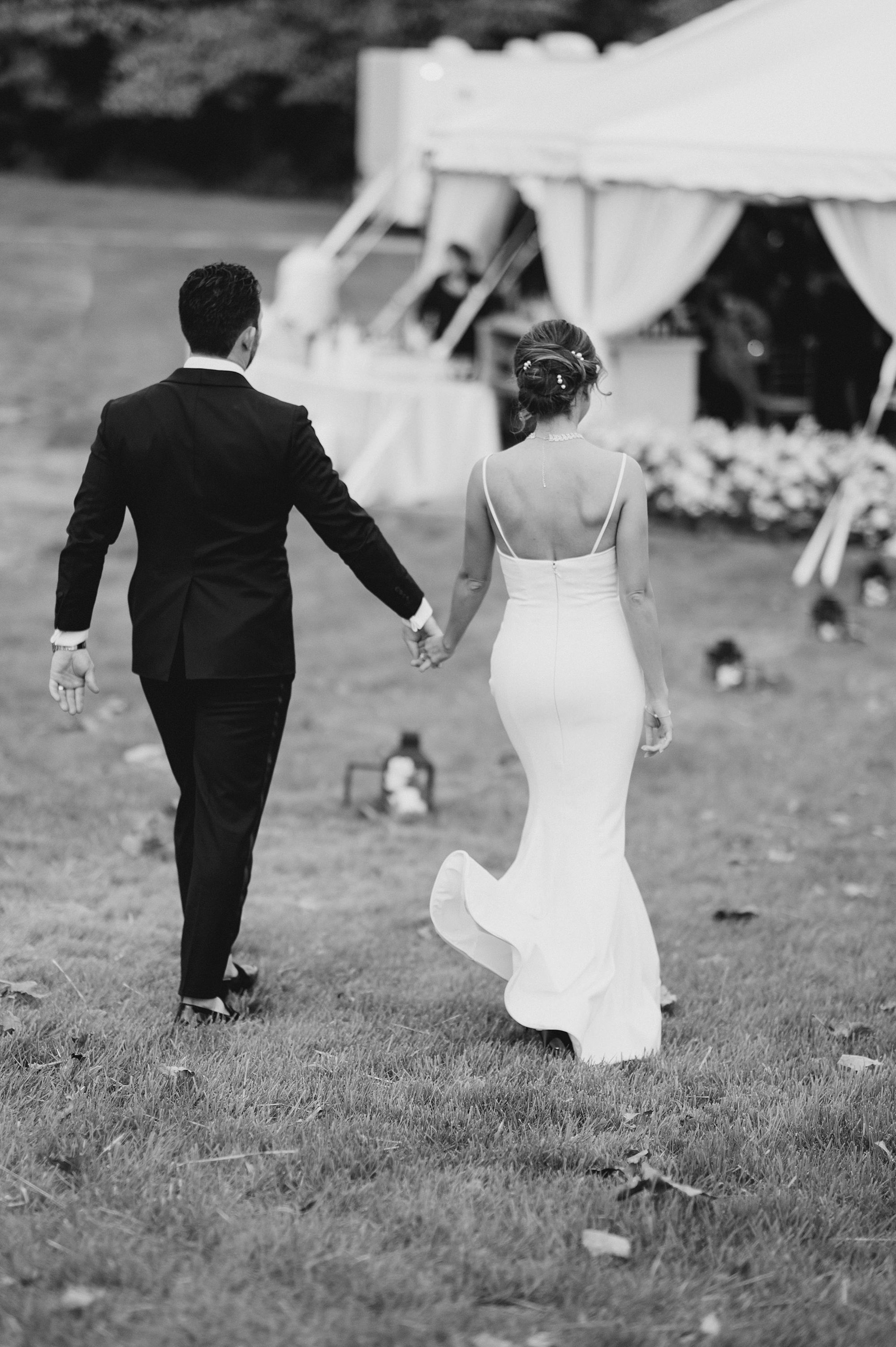 couple walk into outdoor tented wedding reception