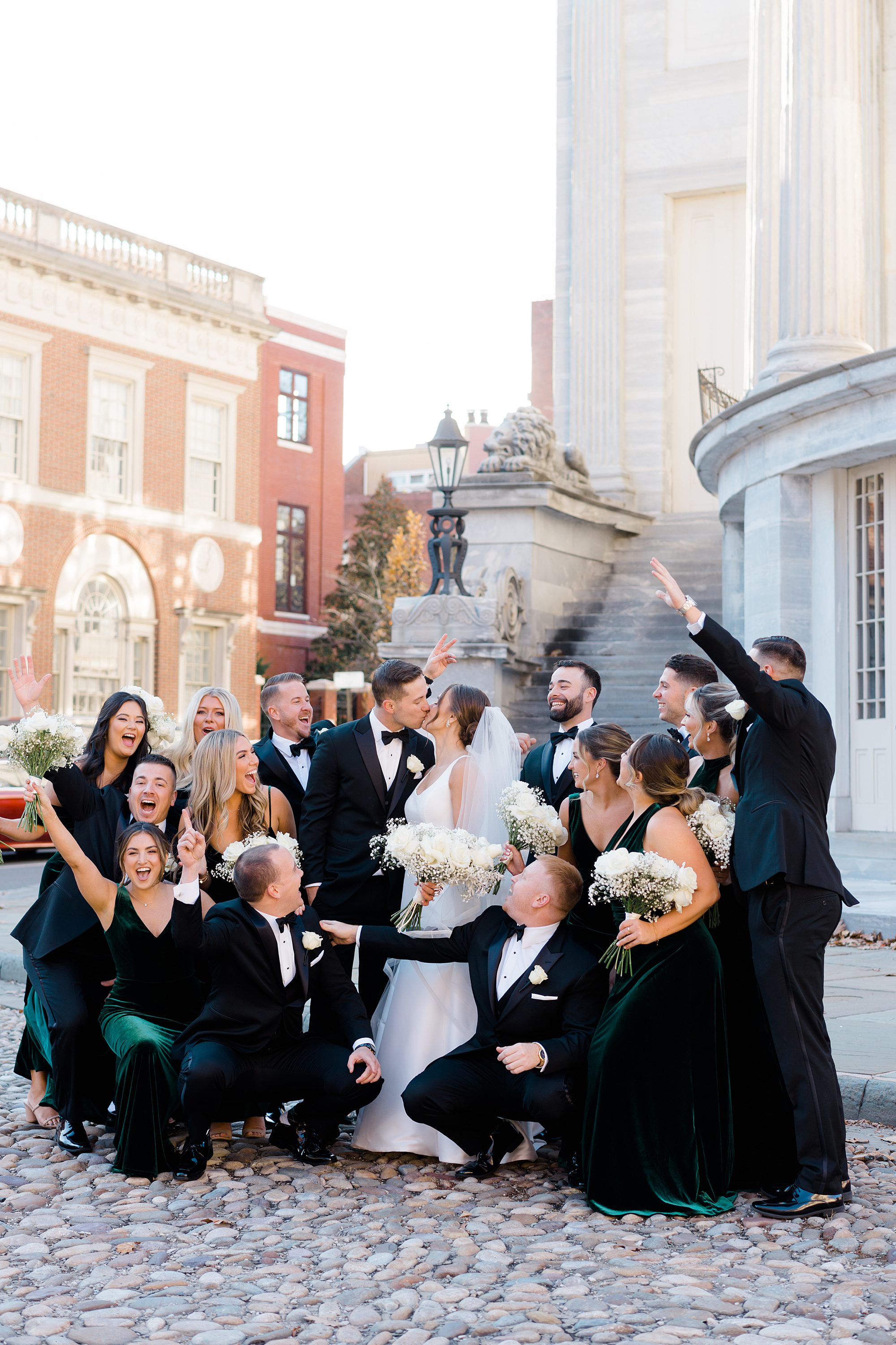 wedding party cheers as bride and groom kiss