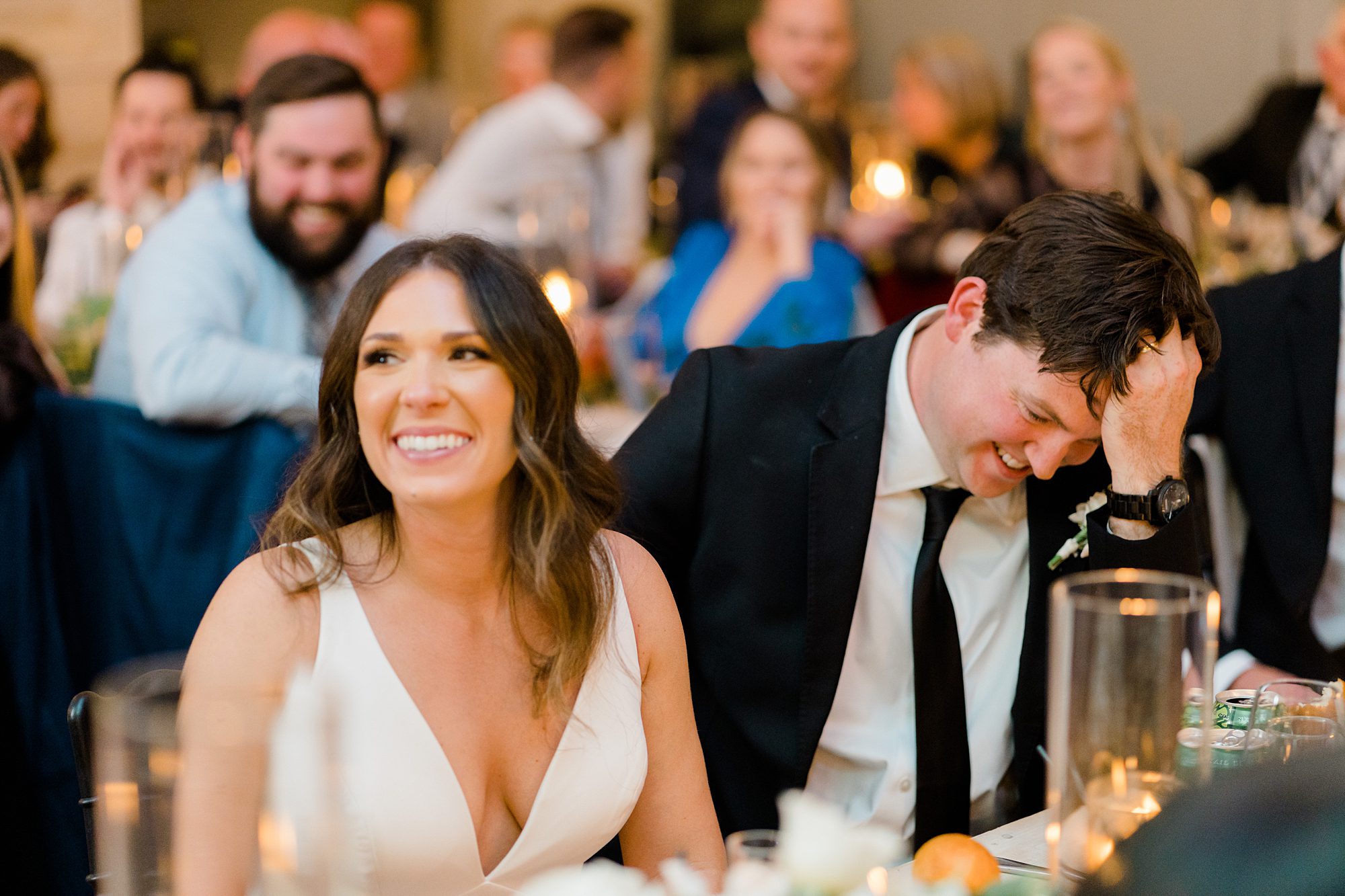 newlyweds laugh as they listen to wedding toast